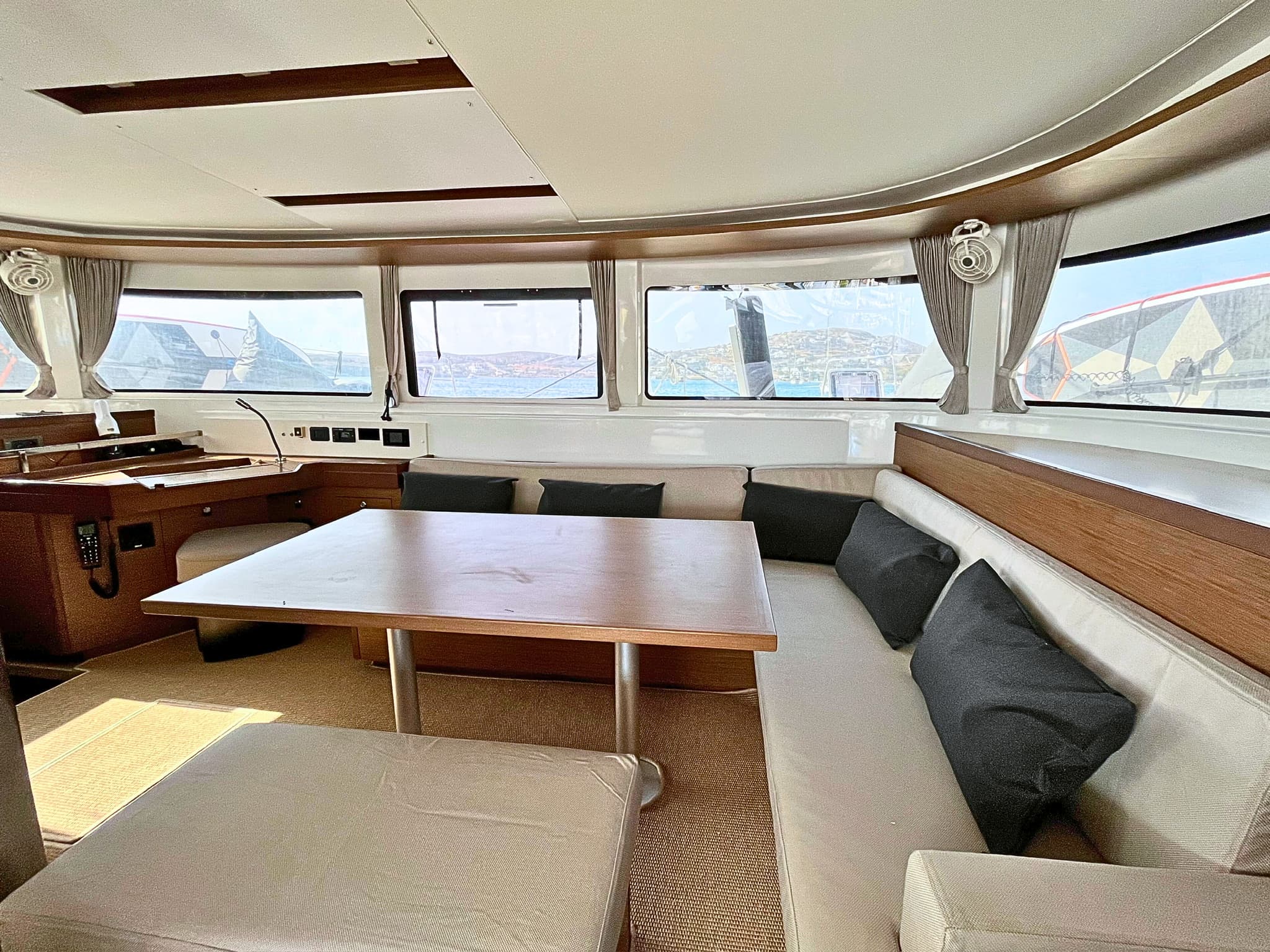 The saloon: dining table with wraparound bench seating and curved windows looking out over the harbour